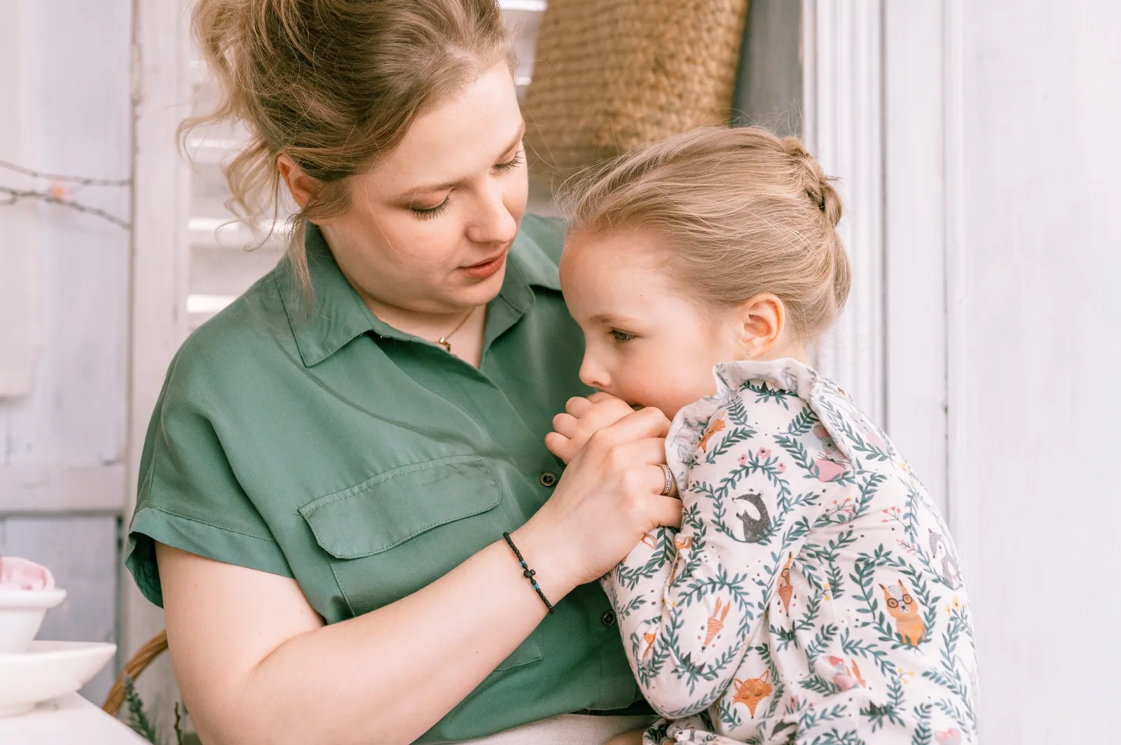A caregiver holding a small child who is leaning into her shoulder